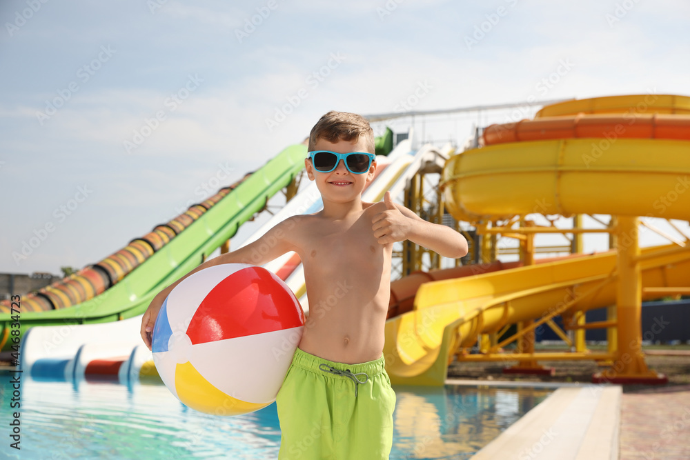 Cute little boy with inflatable ball near pool in water park