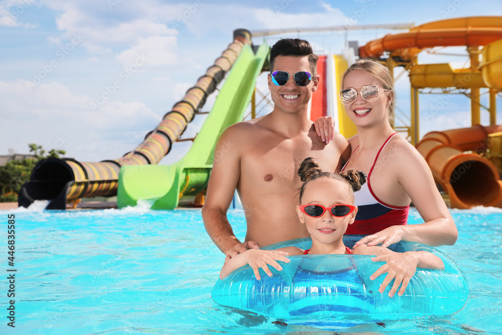 Happy family with inflatable ring in swimming pool at water park, space for text Happy family with inflatable ring in swimming pool at water park, space for text