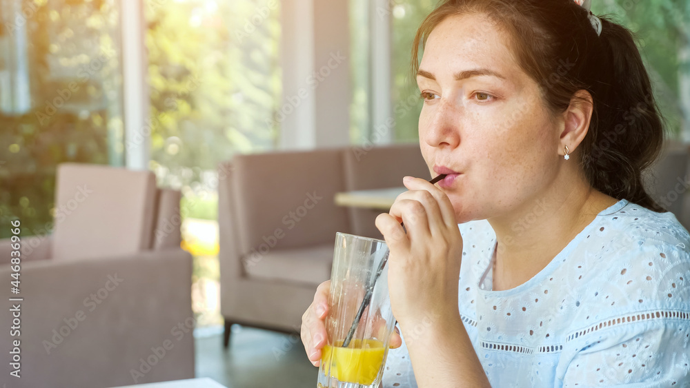 Attractive young lady drinks juice in cafe, side view Attractive young lady drinks juice in cafe, side view