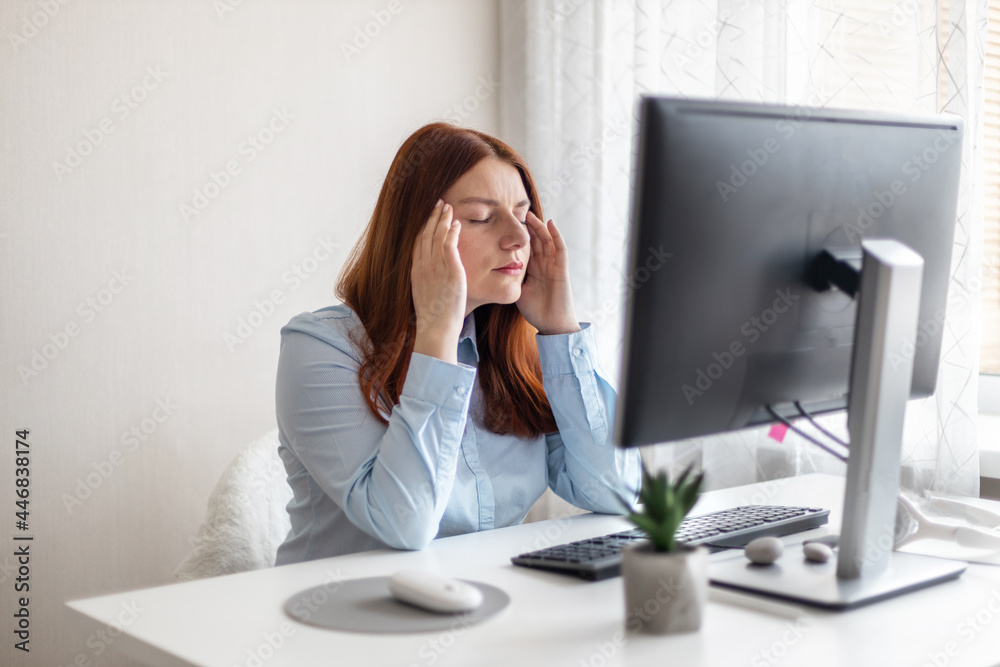 Young Caucasian women are stressed and tired from work at a white desk with a computer at home Young Caucasian women are stressed and tired from work at a white desk with a computer at home