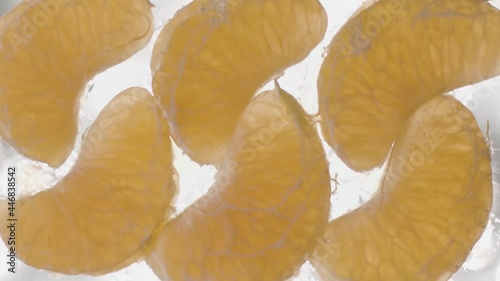 peeled halved tangerine on white backgroundConcept of healthy diet and vitamins. Stock footage. Close up bottom view of peeled tangerine slices lying on glass transparent surface that is being filled photo