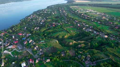 Beautiful village near river Dnieper from the top view, Stari Kodaky, Dnipro, Ukraine, Europe. Green hills, blue water, roofs of small buildings. Drone view, moving toward horizon, 4k. photo