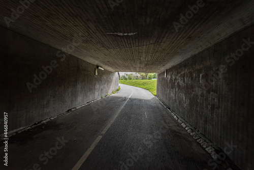 A dark bike underpass with a curve in the end of the tunnel.
