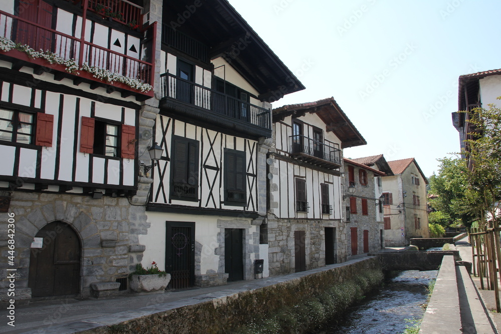 Typical colorful Basque houses with a canal with water passing in front of the street, in Lesaka