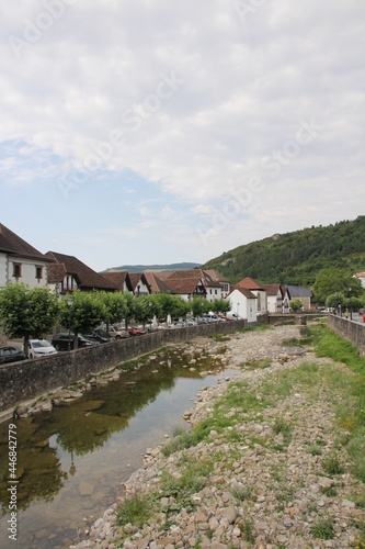 River with stones and vegetation and typical houses with a cloudy sky in Otsagabia, Navarra