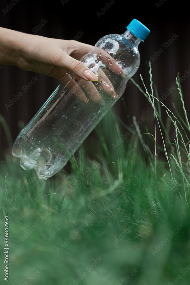 Ecology concept. Person throws a plastic bottle into the grass