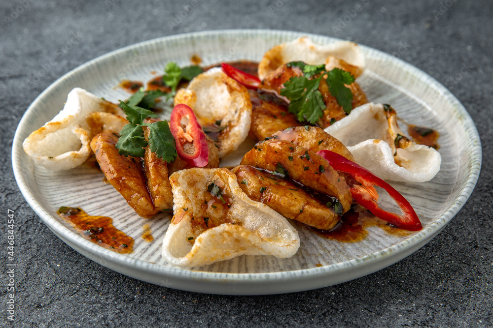 Grilled squid with rice chips sauce. Ready menu for the restaurant. Neutral gray blue textured background Grilled squid with rice chips sauce. Ready menu for the restaurant. Neutral gray blue textured background
