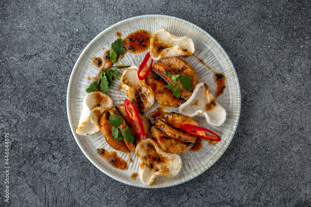 Grilled squid with rice chips sauce. Ready menu for the restaurant. Neutral gray blue textured background Grilled squid with rice chips sauce. Ready menu for the restaurant. Neutral gray blue textured background