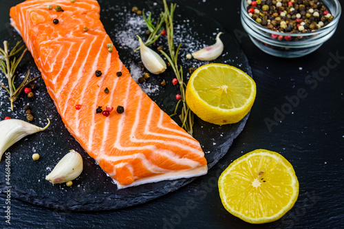 Raw fillet of salmon fish and spices on a slate board