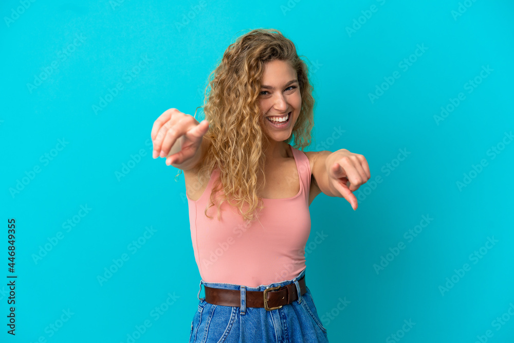 Young blonde woman isolated on blue background pointing front with happy expression Young blonde woman isolated on blue background pointing front with happy expression