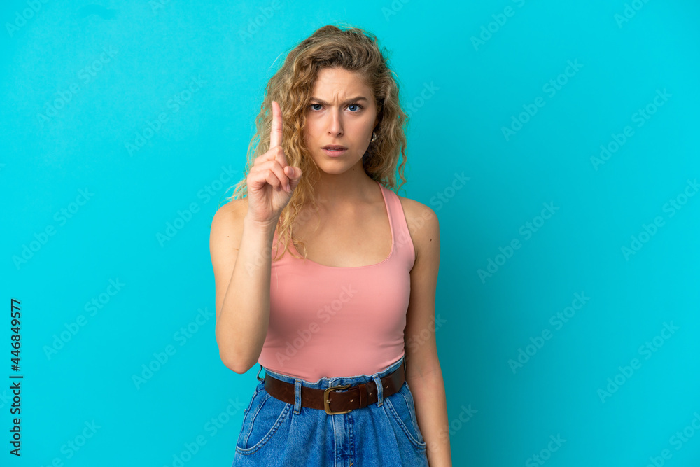 Young blonde woman isolated on blue background counting one with serious expression Young blonde woman isolated on blue background counting one with serious expression