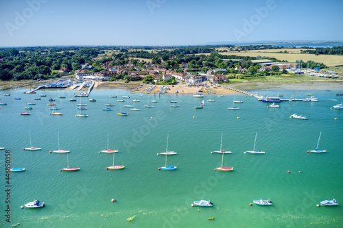 Itchenor West Sussex with sailing boats moored in the estuary and on the wooden jetty set in the beautiful countryside of Southern England. Aerial Photo. photo