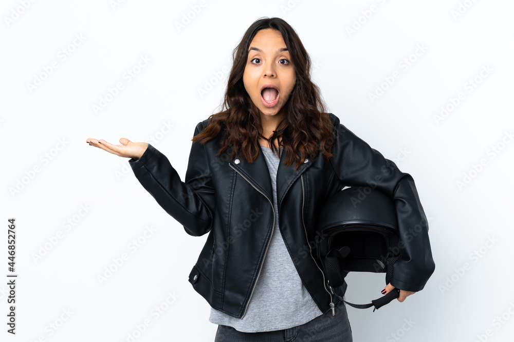 Young woman holding a motorcycle helmet over isolated white background with shocked facial expression Young woman holding a motorcycle helmet over isolated white background with shocked facial expression
