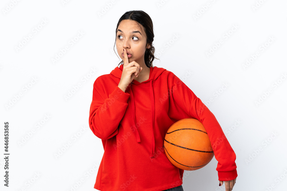 Young woman playing basketball over isolated white background showing a sign of silence gesture putting finger in mouth