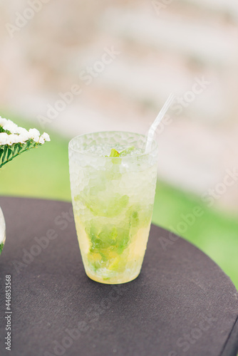  Mojito cocktail with lime and mint with a straw, stands on the table. Summer refreshing lemonade.