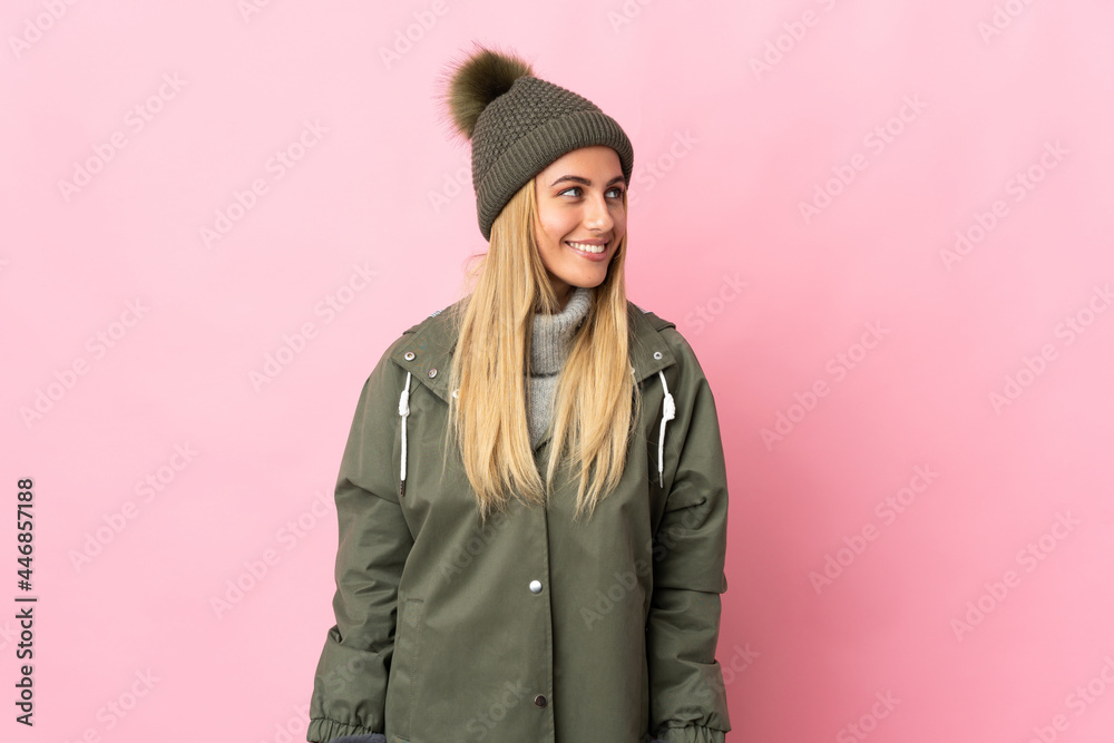 Young woman with winter hat isolated on pink background looking to the side and smiling Young woman with winter hat isolated on pink background looking to the side and smiling