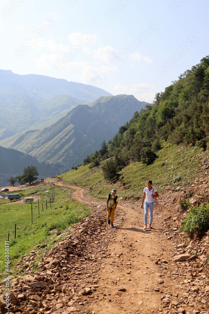 tourist family - mother and son hiking on mountain road to ancient abandoned village Gamsutl in Dagestan