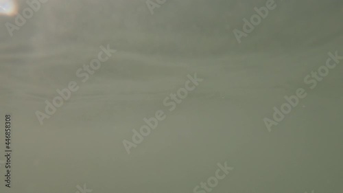 Pov drowning person floating on wea wateer surface with waves pushing him underwater photo