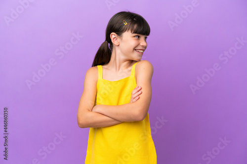 Little caucasian kid isolated on purple background with arms crossed and happy
