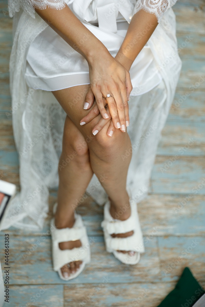 The bride sits with her legs crossed. She has a diamond in her hand.