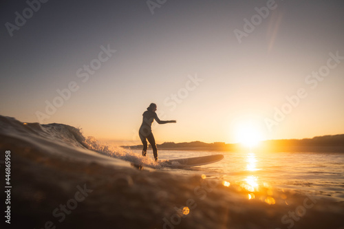 A woman surfer catches a wave at sunrise