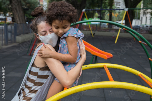 Mother and daughter hugging at playground outside in pandemic life