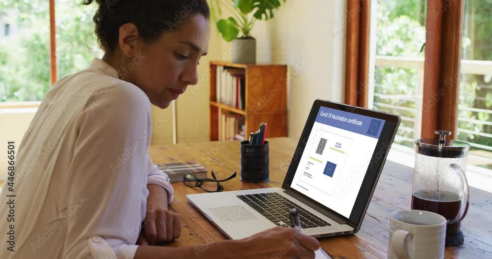 Woman working at desk, covid vaccination certificate with qr code and eu flag on laptop screen Woman working at desk, covid vaccination certificate with qr code and eu flag on laptop screen