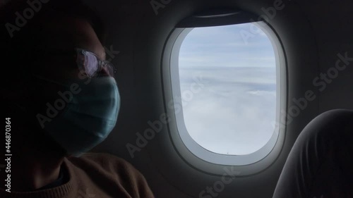 A man wears a face mask and look the sky by an airplane window, pandem photo