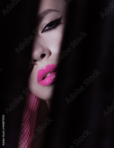 Close-up beauty shot of young pretty model with bright cat-eye make-up. Black Eyeliner. Pink lips. Gorgeous beauty portait