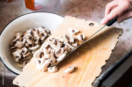 Cooking of mushroom soup. Slicing champignons with a knife photo
