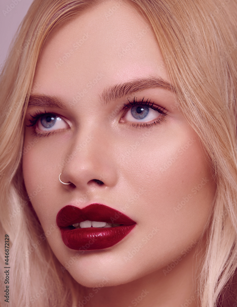 Beauty fashion model portrait with shiny blonde hairstyle with red lips on pink background