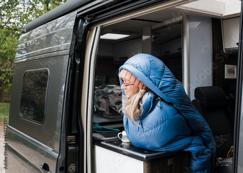 woman sat enjoying a cup of coffee in her sleeping bag in her camper photo