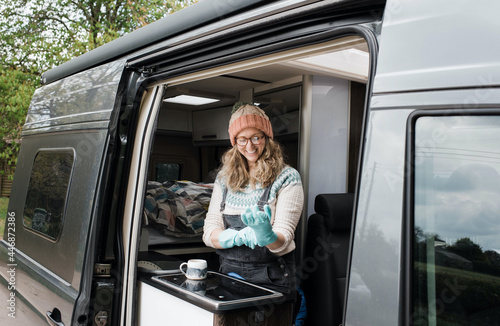 woman putting rubber gloves on in her camper van washing up happily photo