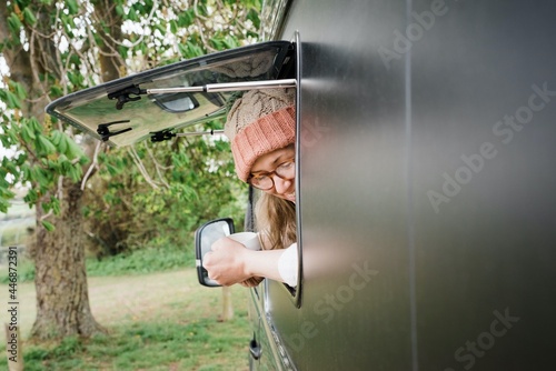 woman looking out of her camper window smiling enjoying a cup of tea photo