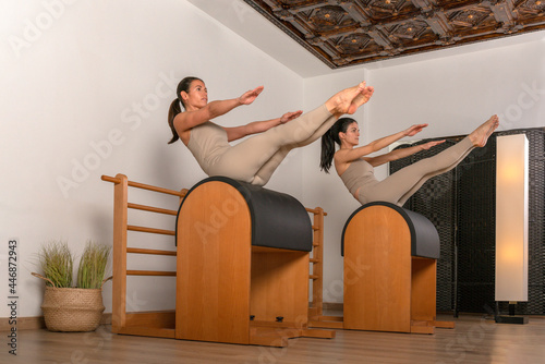 two girls doing pilates exercise teaser