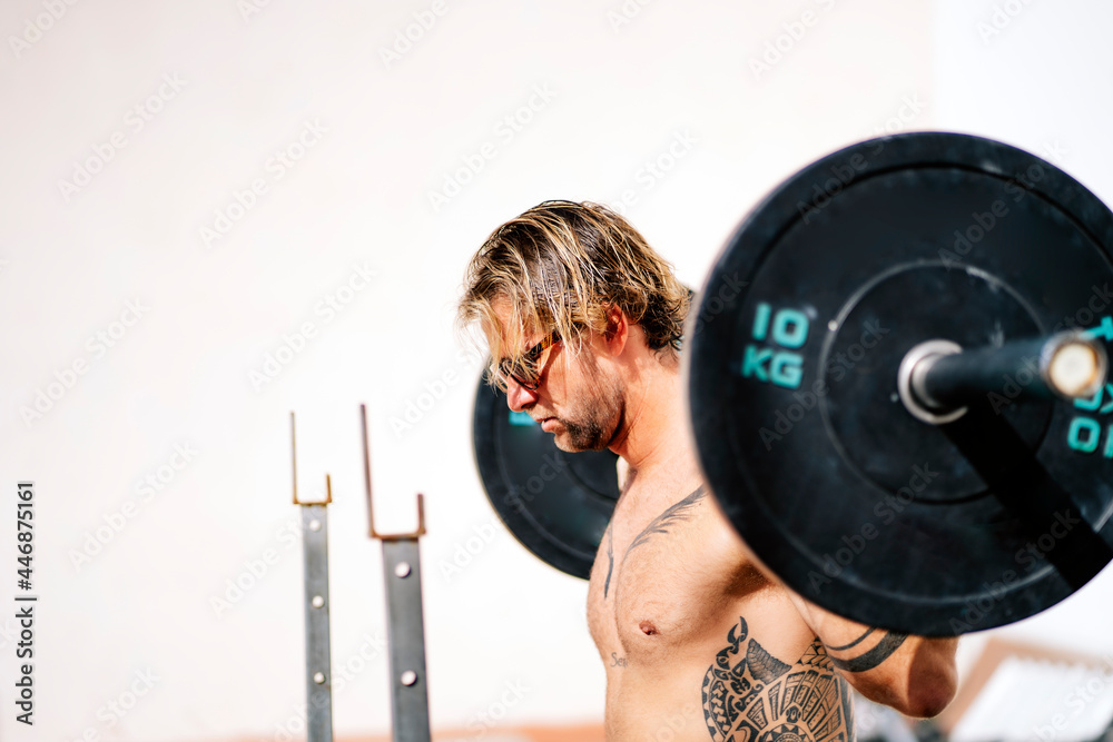 Blond athlete man doing squats with dumbbells Blond athlete man doing squats with dumbbells