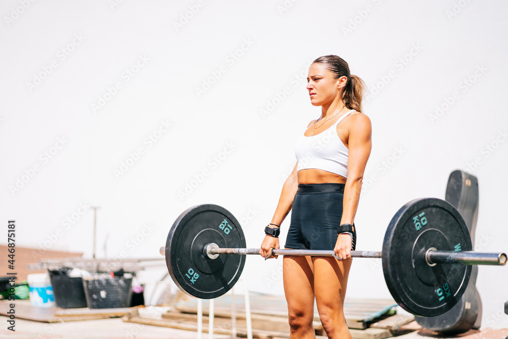 A strong woman performing deadlift with dumbbells outdoors A strong woman performing deadlift with dumbbells outdoors