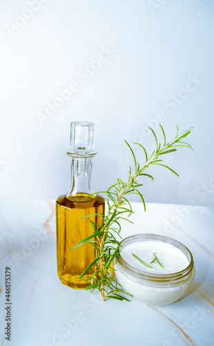 Oil, aromatic herb of rosemary and cream on marble base with white bac photo