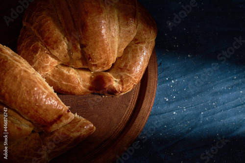 A croissant cut in half on top of a full croissant on blue abstract background © Fabián Montaño