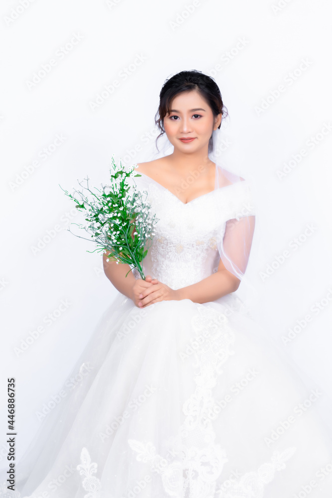 Asian middle-aged woman wearing a bride's dress holding a white flower sitting on a chair behind white background Asian middle-aged woman wearing a bride's dress holding a white flower sitting on a chair behind white background