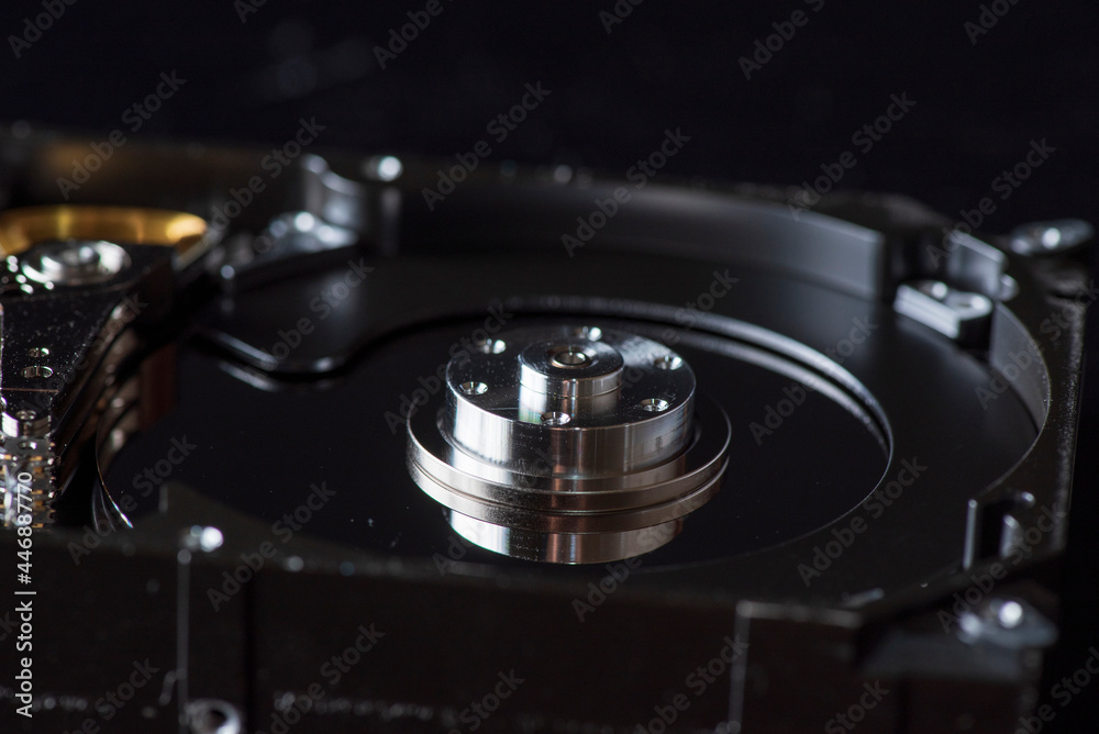 Fragment of a disassembled hard drive, against a dark background. Fragment of a disassembled hard drive, against a dark background.