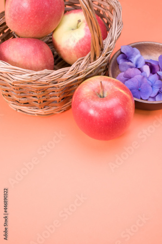 Vertical shot of fresh apples and purple hydrangea flowers isolated on a pink background photo