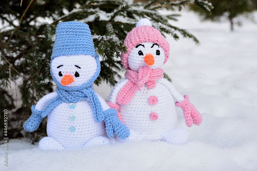 Two knitted snowmen stand in the snow under the tree Two knitted snowmen stand in the snow under the tree