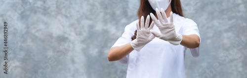 Closeup image of a woman wearing protective face mask and medical rubber gloves showing stop hand sign for Health care and Covid-19 concept