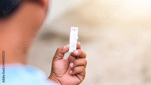 Negative test result by using rapid test device for COVID-19.Express corona test at home  Close up of young man holding a negative covid antigen test.