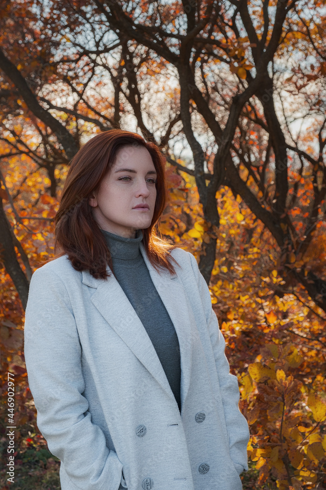 A cute redheaded woman in good spirits poses on an autumn day A cute redheaded woman in good spirits poses on an autumn day