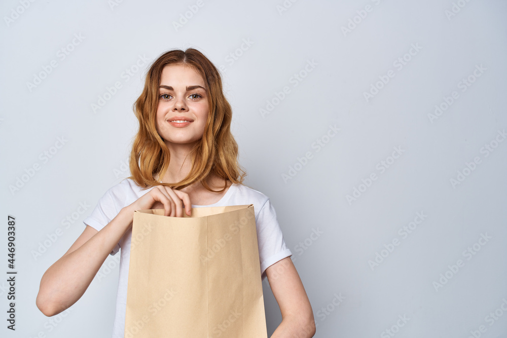 woman with paper bag in her hands Shopping fun light background woman with paper bag in her hands Shopping fun light background