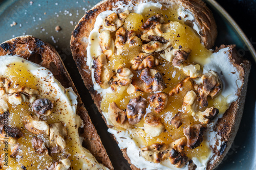 Two bread toast with cream cheese, roasted walnuts, honey, pepper and salt, close up, top view