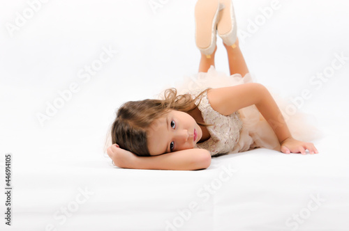 Portrait of happy pretty curly little girl laying on the floor and posing over white background   happy face girl concept