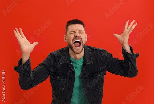 Angry man yelling on red background. Hate concept